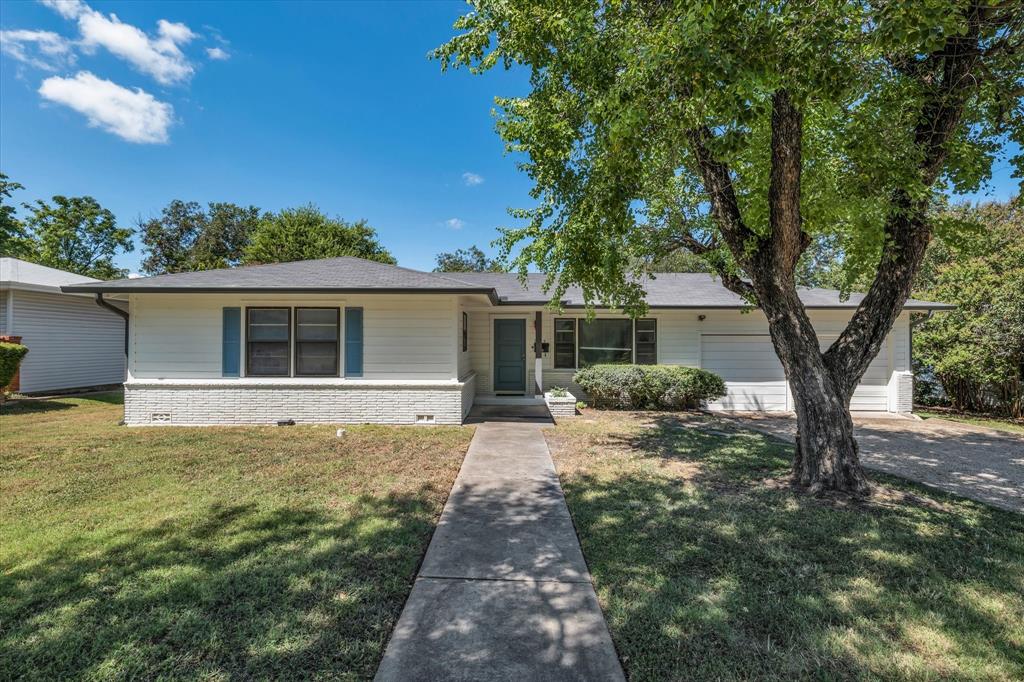 Single story home featuring brick siding, a front lawn, an attached garage, and driveway