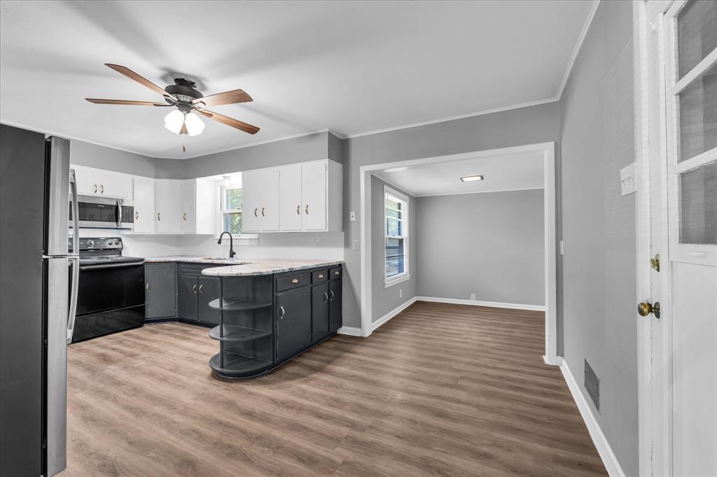 1325 Sunset Street Waco, TX 76710 - Photo 13 of 40 Kitchen featuring stainless steel appliances, dark wood-style floors, a ceiling fan, ornamental molding, and white cabinetry