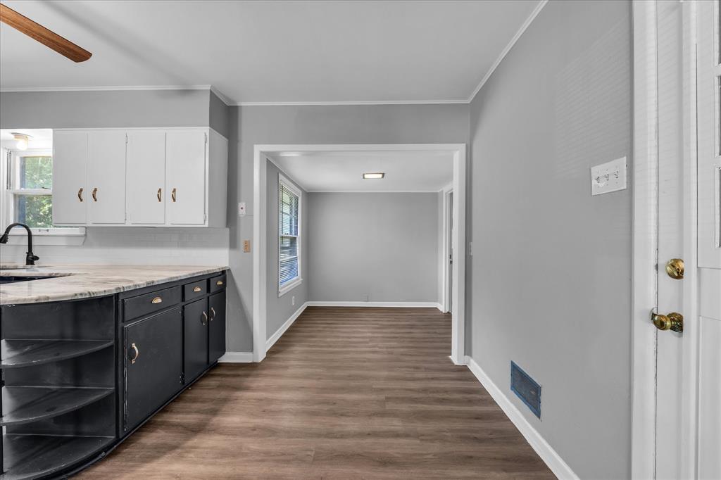 1325 Sunset Street Waco, TX 76710 - Photo 14 of 40 Kitchen with white cabinets, dark wood-style floors, light stone countertops, crown molding, and open shelves