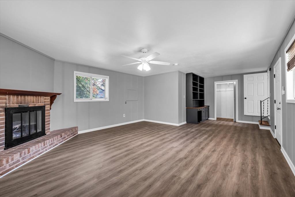 1325 Sunset Street Waco, TX 76710 - Photo 17 of 40 Unfurnished living room featuring dark wood-style floors, a fireplace, a ceiling fan, and stairs