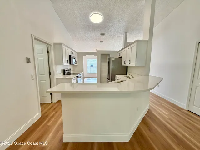 a kitchen with stainless steel appliances a refrigerator sink and wooden floor