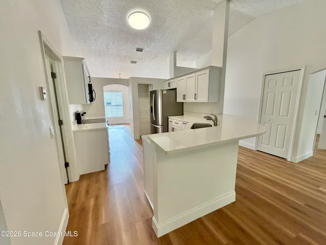 a kitchen with stainless steel appliances white cabinets and a wooden floor