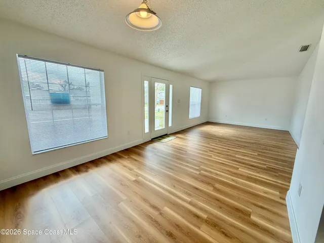 a view of empty room with wooden floor and fan