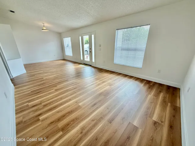 a view of empty room with wooden floor and ceiling fan