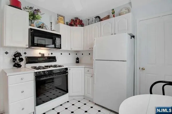 a white kitchen with a stove a sink and a refrigerator