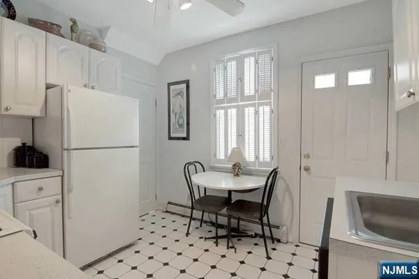 a white kitchen with a refrigerator a stove a sink and a window