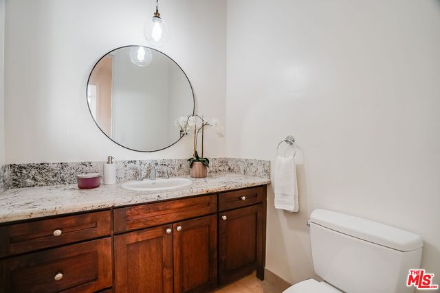 a bathroom with a granite countertop toilet sink and mirror