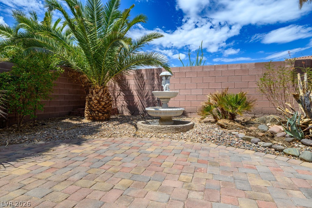 3591 Driving Range Street Las Vegas, NV 89122 - Photo 29 of 79 This tranquil outdoor space features a decorative fountain and lush palm trees, perfect for relaxation.