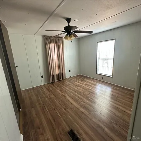 an empty room with wooden floor fan and windows