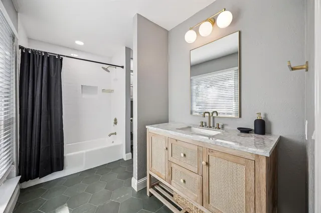 a spacious bathroom with a granite countertop sink mirror and a bathtub
