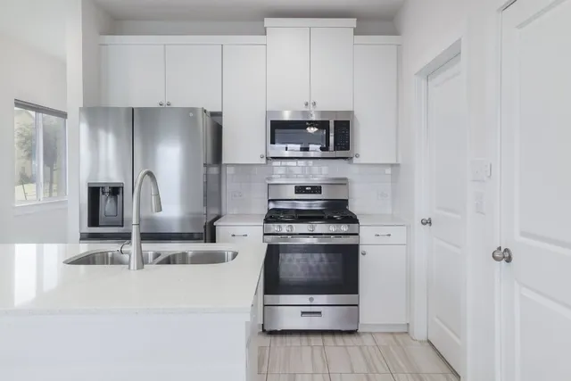 a kitchen with stainless steel appliances a refrigerator sink and stove