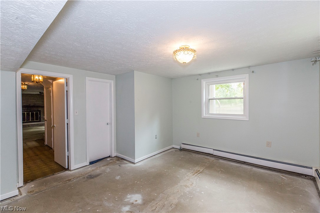 3077 Luli Road Mogadore, OH 44260 - Photo 24 of 34 Unfurnished bedroom with baseboard heating, concrete flooring, and a textured ceiling