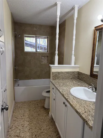 a bathroom with a granite countertop sink a toilet and bathtub