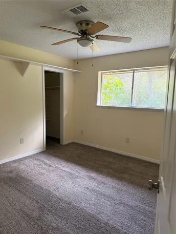 an empty room with a window and a ceiling fan
