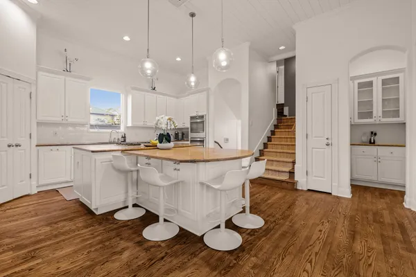 a kitchen with stainless steel appliances granite countertop a stove a sink a refrigerator and white cabinets with wooden floor