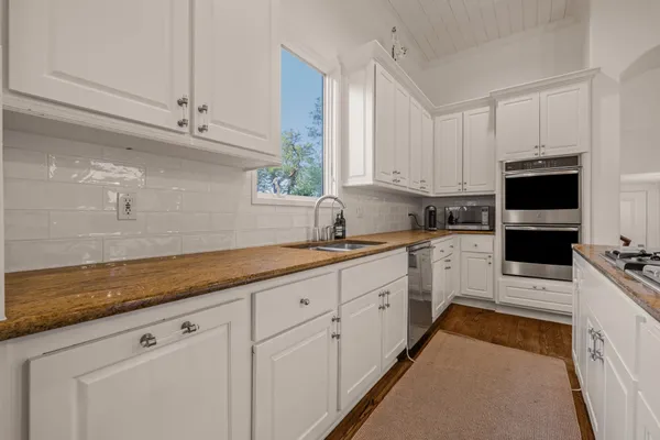 a kitchen with granite countertop white cabinets stainless steel appliances and a counter space