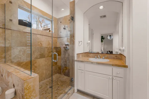 a bathroom with a granite countertop sink a mirror and a shower