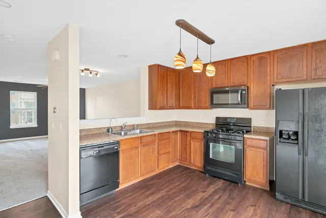 a kitchen with stainless steel appliances granite countertop a sink a stove a refrigerator cabinets and wooden floor