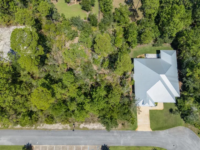 an aerial view of a house with yard and trees in the background