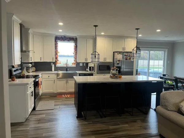 a kitchen with kitchen island granite countertop a sink cabinets and wooden floor