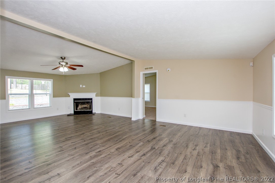 246 Loop Road Raeford, NC 28376 - Photo 11 of 42 an empty room with wooden floor chandelier and windows