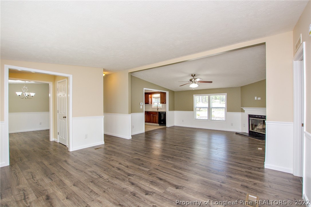 246 Loop Road Raeford, NC 28376 - Photo 12 of 42 an empty room with wooden floor chandelier and windows