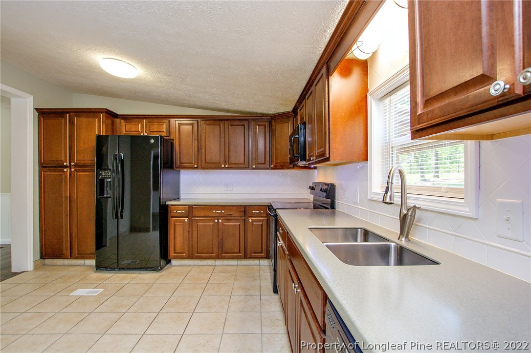 246 Loop Road Raeford, NC 28376 - Photo 16 of 42 a kitchen with a sink a refrigerator and cabinets