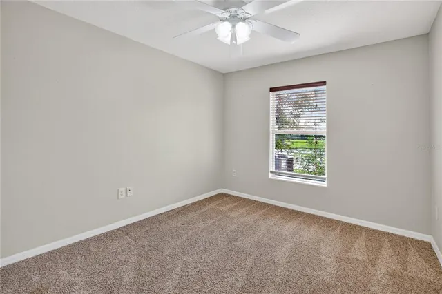 an empty room with a window and a fan