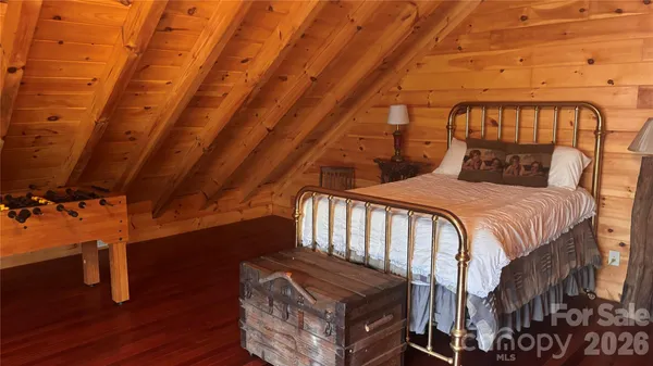 a bedroom with a bed a dresser and wooden floor