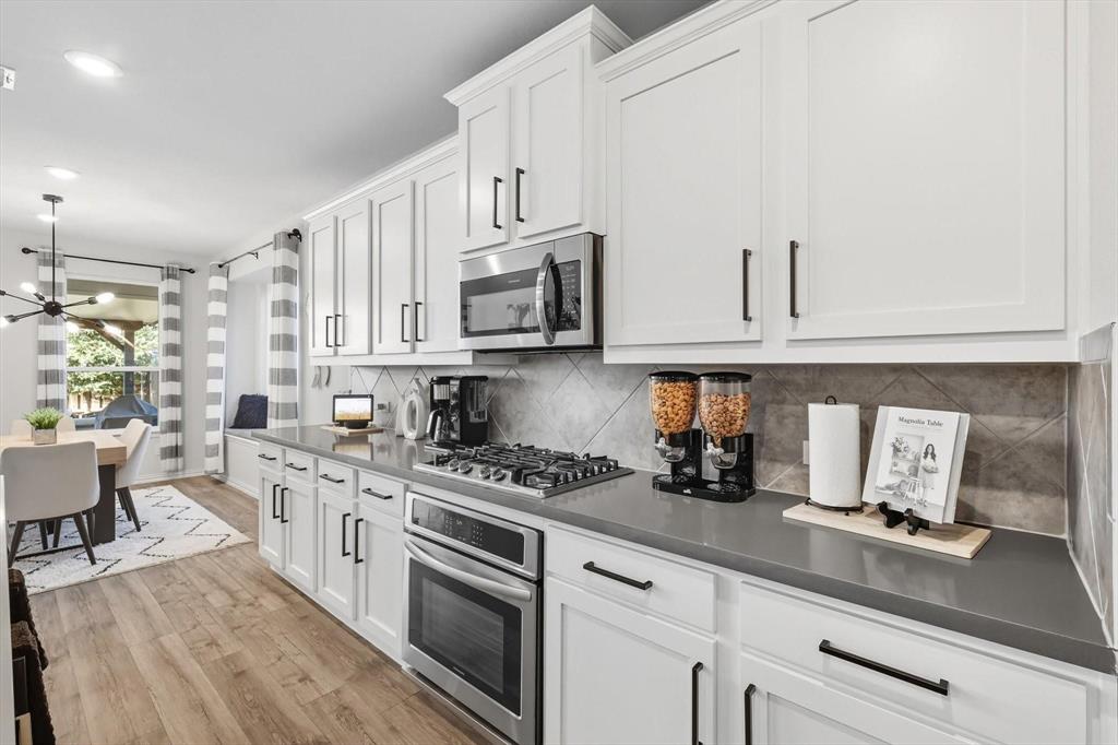 1724 Wassel Road Fort Worth, TX 76052 - Photo 8 of 24 Modern kitchen featuring white shaker cabinetry, dark countertops, stainless steel appliances, and a tiled backsplash