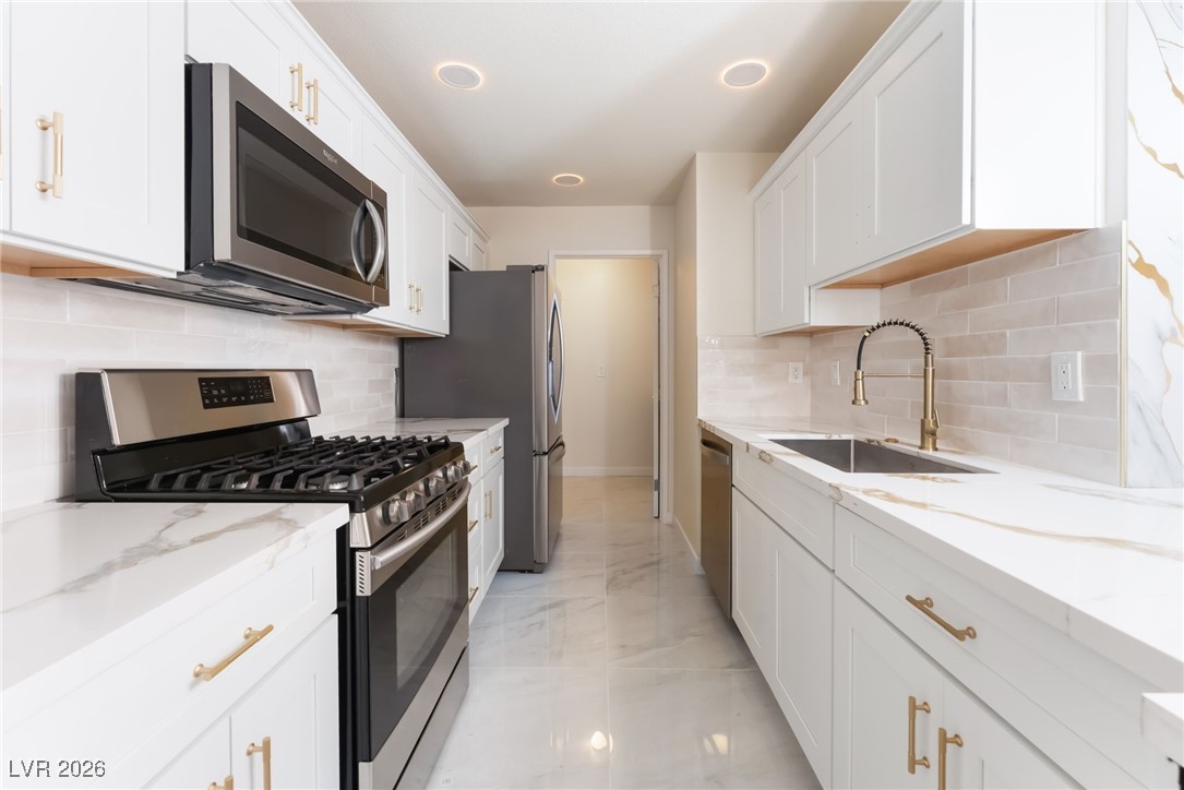 2200 South Fort Apache Road, Unit 1101 Las Vegas, NV 89117 - Photo 11 of 42 Kitchen with appliances with stainless steel finishes, white cabinetry, light stone countertops, light marble finish floors, and backsplash