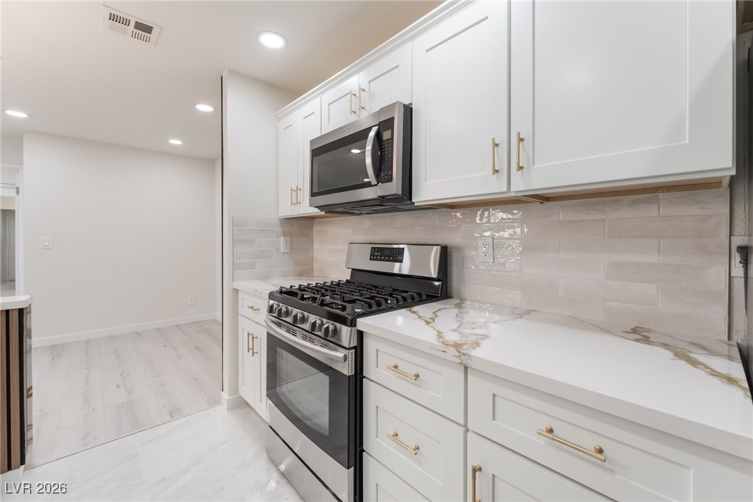 2200 South Fort Apache Road, Unit 1101 Las Vegas, NV 89117 - Photo 13 of 42 Kitchen featuring appliances with stainless steel finishes, white cabinets, recessed lighting, decorative backsplash, and light marble finish floors