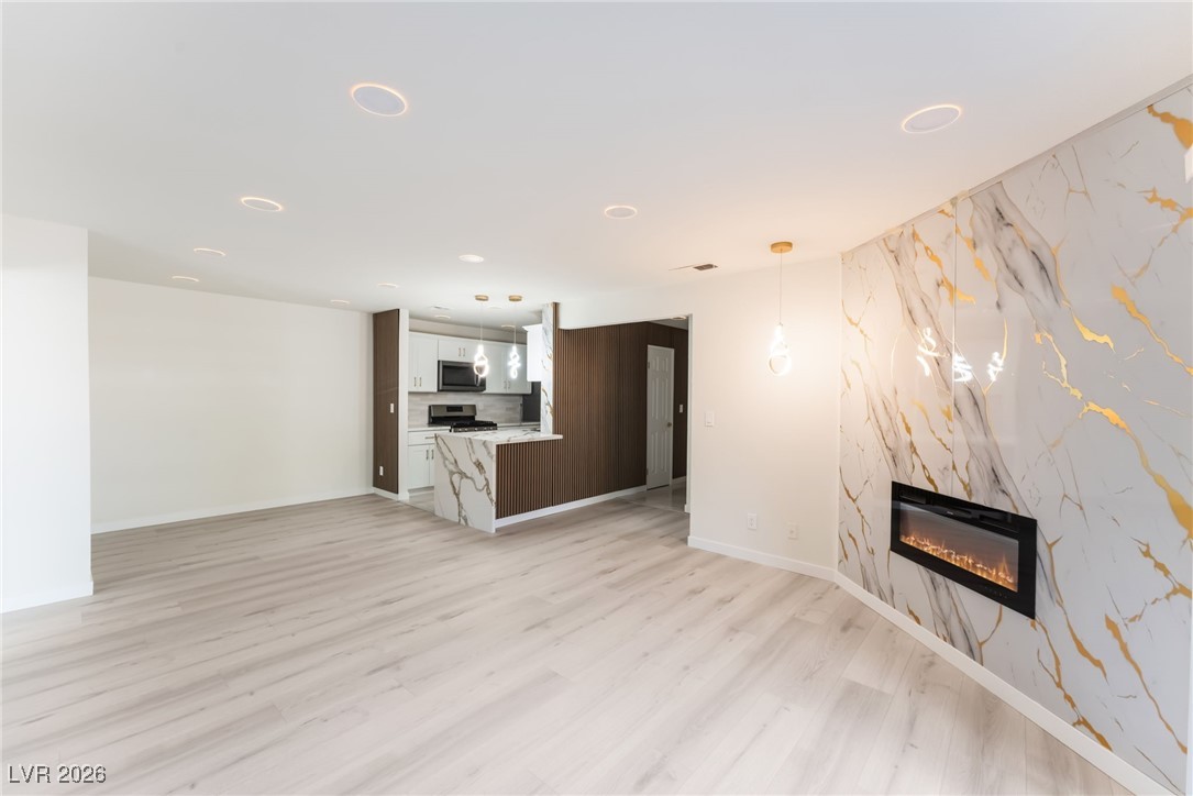 2200 South Fort Apache Road, Unit 1101 Las Vegas, NV 89117 - Photo 7 of 42 Unfurnished living room with an accent wall, a premium fireplace, and light wood-style flooring