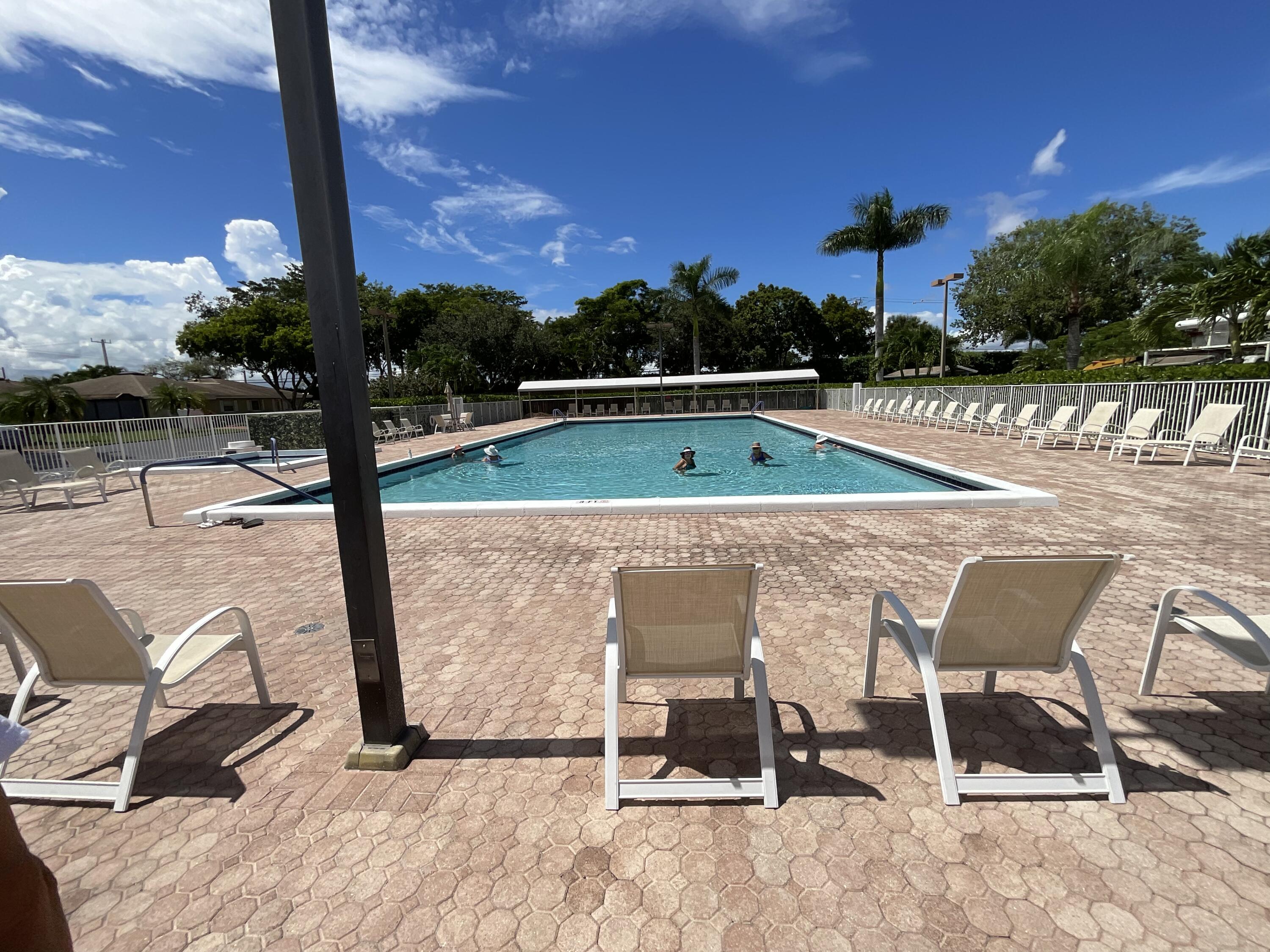 18856 Argosy Drive, Unit C Boca Raton, FL 33496 - Photo 13 of 62 a view of swimming pool with lawn chairs and wooden fence