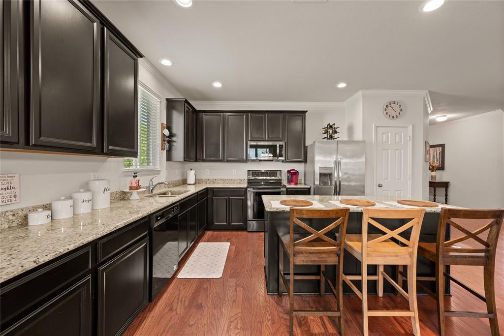 537 Running Water Trail Fort Worth, TX 76131 - Photo 12 of 31 a kitchen with kitchen island granite countertop wooden floors and stainless steel appliances