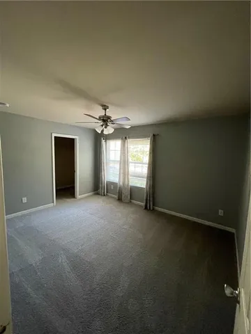 an empty room with windows and chandelier fan