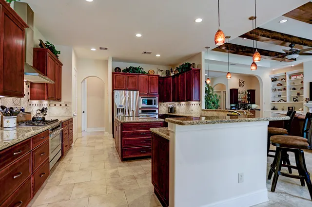 a kitchen with stainless steel appliances kitchen island granite countertop a refrigerator and a stove top oven