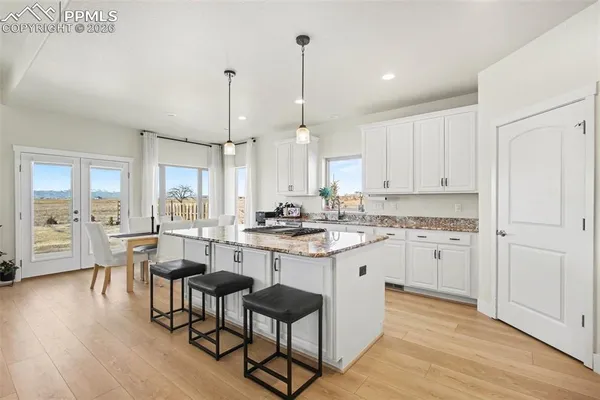 a kitchen with sink stove and white cabinets with wooden floor