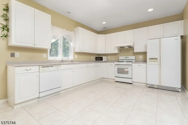 a kitchen with white cabinets stainless steel appliances and a window