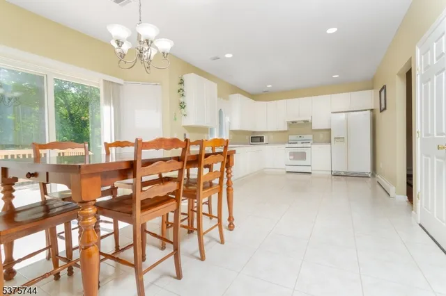 a view of a dining room with furniture a chandelier and large window