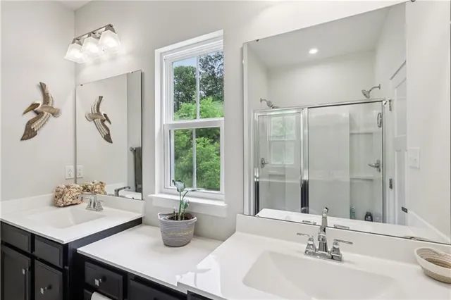 a bathroom with double vanity sinks a mirror and a shower