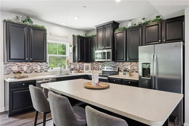 a kitchen with stainless steel appliances a sink a stove a refrigerator cabinets and wooden floor