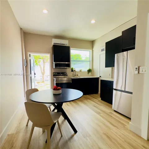 a kitchen with stainless steel appliances a dining table chairs and a refrigerator