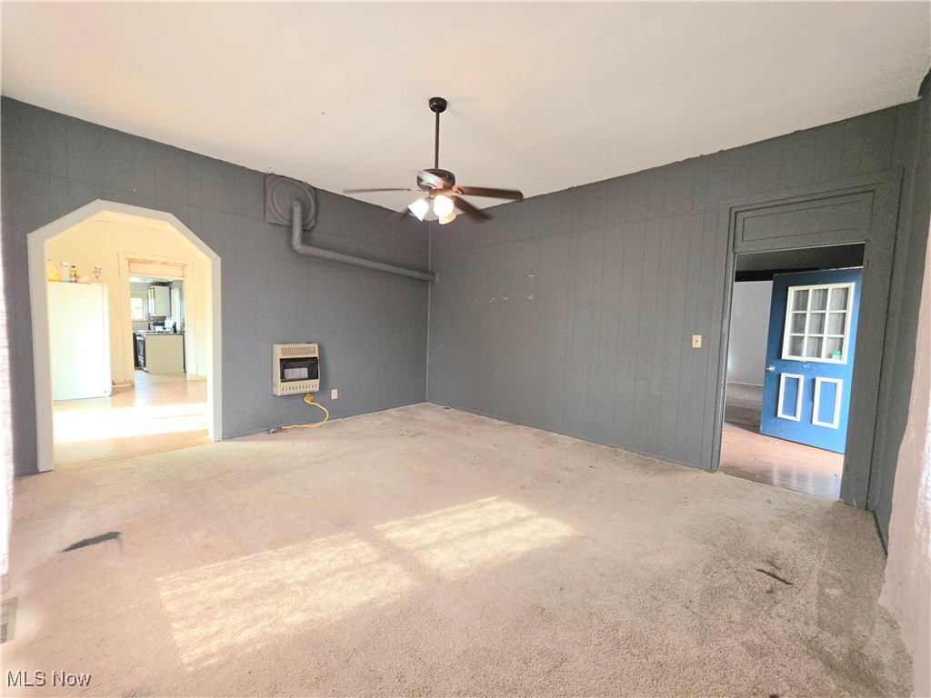 10 Browns Ridge Road Rockport, WV 26169 - Photo 7 of 35 Unfurnished living room with a ceiling fan, arched walkways, heating unit, carpet floors, and wooden walls