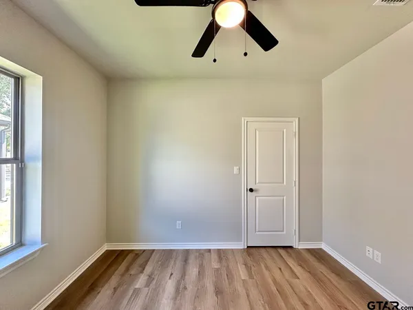 an empty room with wooden floor cabinet and windows