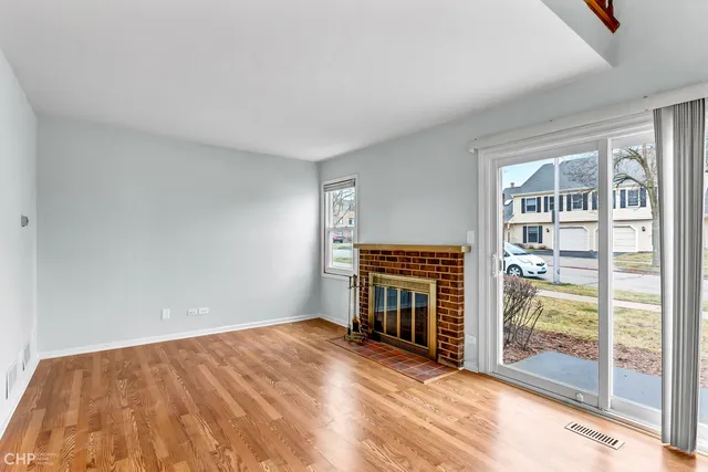 a view of empty room with floor to ceiling window and fireplace