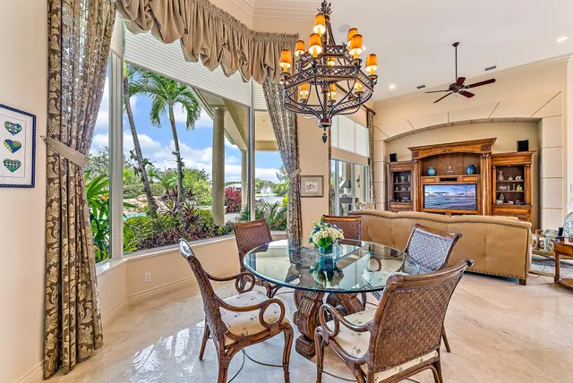 a view of a dining room with furniture a chandelier and large windows