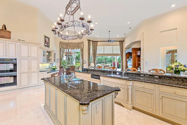 a large kitchen with granite countertop a stove a sink a refrigerator and a wooden cabinets