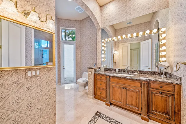 a bathroom with a granite countertop toilet a sink and a large mirror