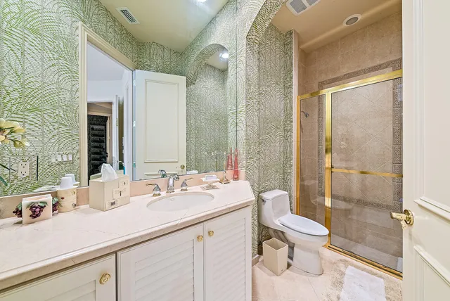 a bathroom with a granite countertop toilet sink and mirror